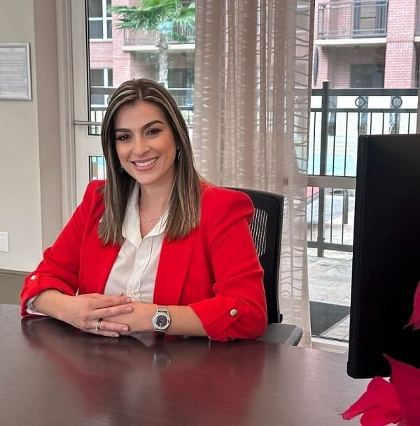 lina aguilar en un escritorio con blazer rojo